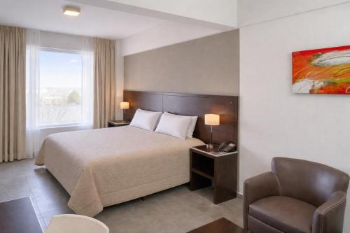 a hotel room with a bed and a chair at Hotel NEU 354 in Neuquén