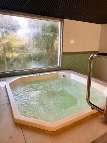 a bath tub filled with water next to a window at Apartamento quarto e sala, varanda com vista para a Pedra Azul e cozinha completa no Condomínio Vista Azul in Pedra Azul