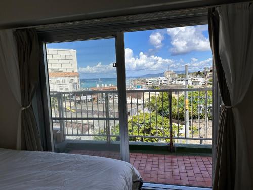 a bedroom with a view of the ocean from a balcony at Prince Plage OKINAWA 6F in Fuzuchi