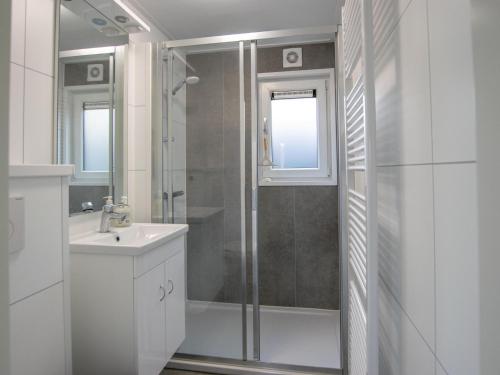 a white bathroom with a shower and a sink at De Huismus in Heiloo