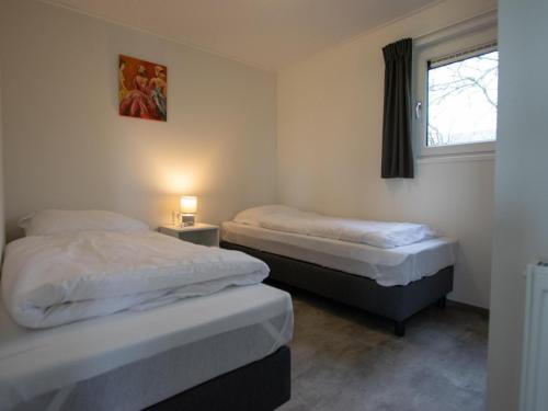 two twin beds in a room with a window at De Huismus in Heiloo