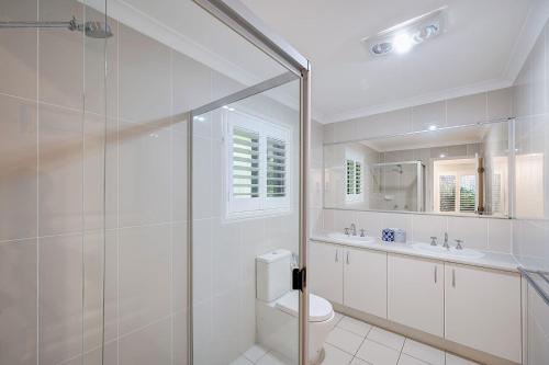a bathroom with a shower and a toilet and a sink at Hideaway -4BR Family Home with Pool, Near Beach in Caloundra