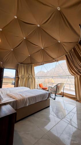 a bedroom with a large bed and a large window at Victoria Luxury camp in Wadi Rum