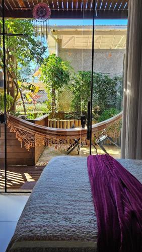 a hammock in a bedroom with a view of a garden at Casa da Flor Guest House – Praia Grande – Beto Carrero in Penha