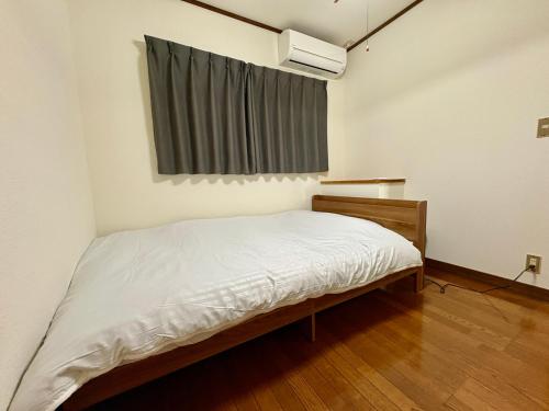 a small bedroom with a bed and a window at Stay Plus Azunoa in Oyama