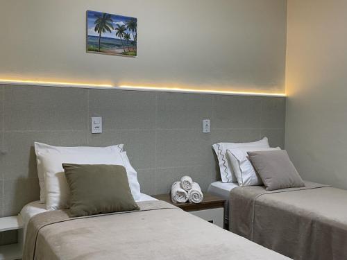 ein Hotelzimmer mit zwei Betten und einer Uhr in der Unterkunft Flow Pousada in Maringá