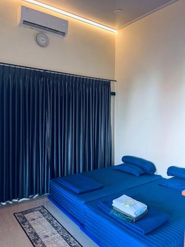 a bedroom with two blue beds and a window at Lora House in Sukoharjo