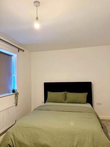 a bedroom with a bed with a black headboard and a window at Elegant King Room with Wifi & Parking in Milton Keynes