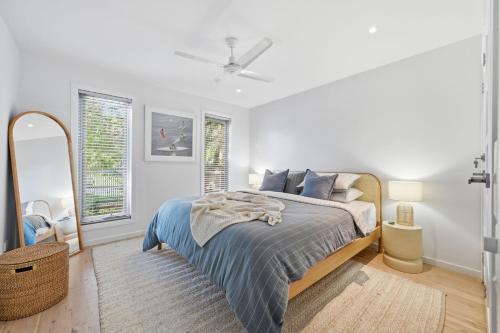 a white bedroom with a bed and a mirror at Tamara Coastal Retreat in Inverloch