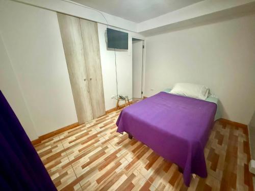 a bedroom with a purple bed and a wooden floor at Le Grey Arica in Arica