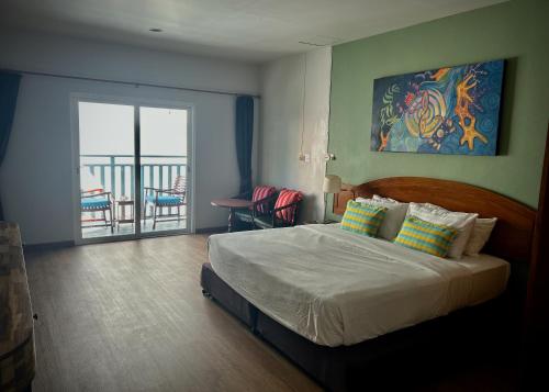 a bedroom with a bed with a view of a balcony at Sugar and Spice Inn in Kata Beach