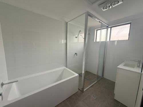 a white bathroom with a tub and a sink at The Cove in Scotts Head