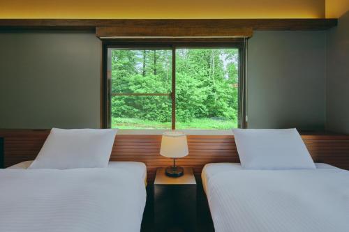 two beds in a room with a window at Villa El Cielo Myoko in Myoko