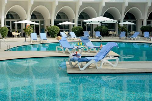 a woman sitting in a chair next to a swimming pool at Kenzi Solazur in Tangier