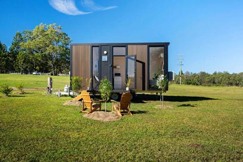 a tiny house sitting on top of a field at Tiny Tallowood by Tiny Away in Glenreagh