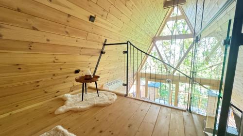 a room with a wooden wall with a table and a window at Fészek Lombház in Kismaros