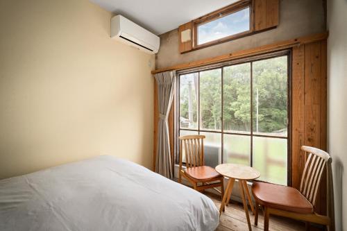 a bedroom with a bed and a window and a table and chairs at The Deer Park Inn in Nara