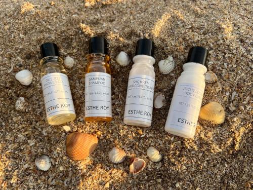 three bottles of essential oils in the sand with shells at Sakura Apartments in Astara