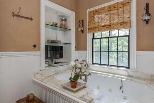 a bathroom with a bath tub with a window and a tub at Villa Grand Horizon in East Hampton