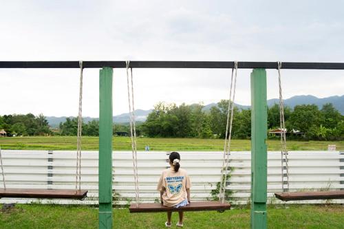 a person sitting on a swing in a field at Butterfly Resort Hostel, Pai in Pai