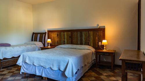 a bedroom with two beds and two lamps on tables at Pousada da Sirlei in Tiradentes