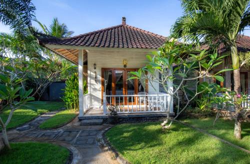 a small house with a porch and palm trees at Blue Lagoon Secret Villas in Nusa Lembongan