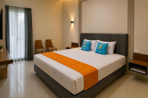 a bedroom with a large bed with blue and orange pillows at SANS Vibes Grand Surya Jember Mini Zoo in Panti