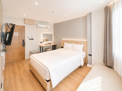 a bedroom with a large white bed and a television at V1 boutique hotel in Kanchanaburi City