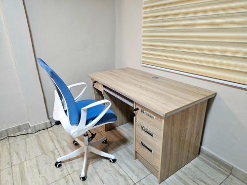 a desk with a blue chair next to a wooden desk at This apartment blends elegance and calm in Mills Center