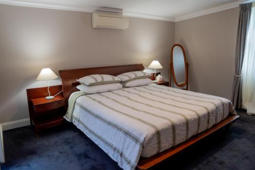 a bedroom with a bed and two lamps and a mirror at Heritage On Horseshoe Guest House in South West Rocks