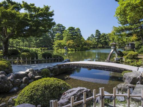 a pond in a garden with a bridge over it at Private Hotel Kanazawa SHIKI in Kanazawa