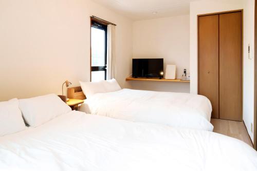 two beds in a room with white sheets at Haul Sakuramachi in Kumamoto