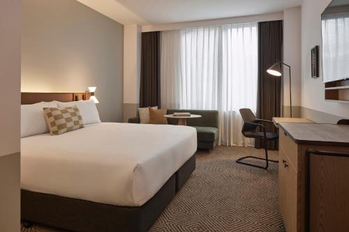a hotel room with a large bed and a desk at Flagstaff Gardens Hotel Melbourne in Melbourne