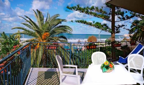 a balcony with white tables and chairs and the beach at Villa Gaia Hotel in Cefalù