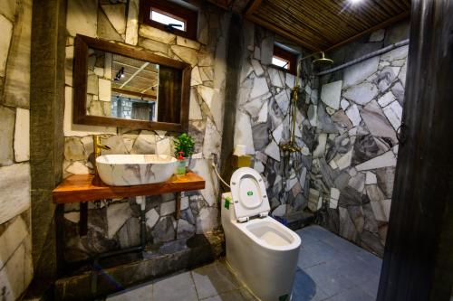 a stone bathroom with a toilet and a sink at homestay bongbang in Ha Giang