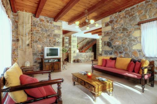 a living room with a couch and a tv at Sea-Sunset Views Villa Lefkothea with Private Pool near Elafonissi in AmigdhalokeFálion