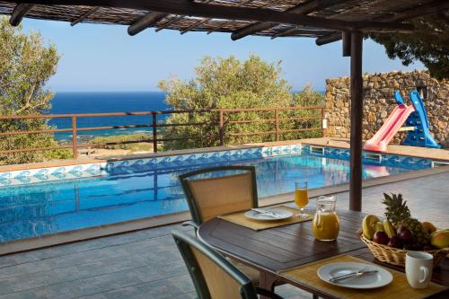 a table and chairs next to a swimming pool at Sea-Sunset Views Villa Lefkothea with Private Pool near Elafonissi in AmigdhalokeFálion
