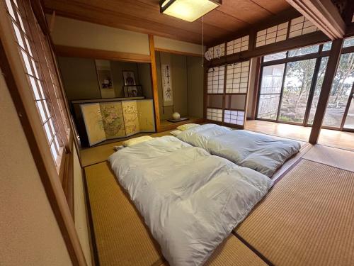 a large bed in a room with windows at 空港近くの温泉宿 翻車魚庵 in Kirishima