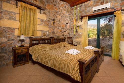 a bedroom with a bed and a stone wall at Sea-Sunset Views Villa Lefkothea with Private Pool near Elafonissi in AmigdhalokeFálion