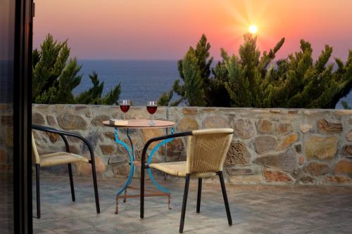 two chairs and a table with two glasses of wine at Sea-Sunset Views Villa Lefkothea with Private Pool near Elafonissi in AmigdhalokeFálion