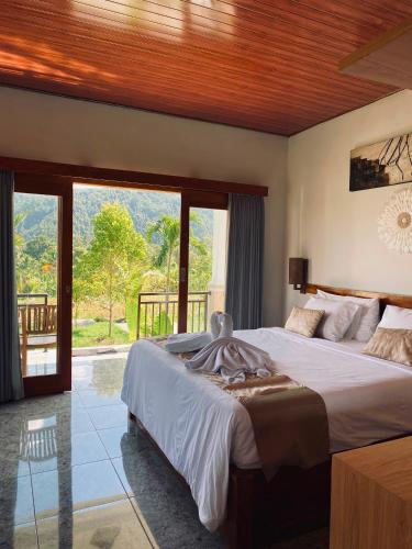 a bedroom with a large bed and a balcony at Umaku Bali Homestay in Munduk