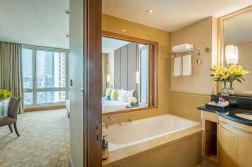 a bathroom with a tub and a large mirror at Ascott Sathorn Bangkok in Bangkok