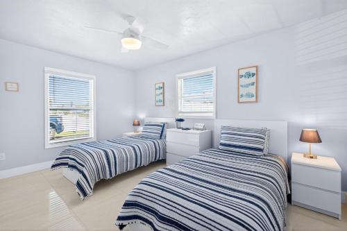 two beds in a bedroom with white walls and windows at Downtown Breeze in Cape Coral
