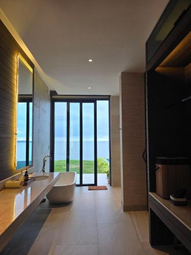 a large bathroom with a tub and a large window at Sabi by the Sea Kep in Kep