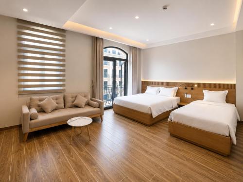 a hotel room with two beds and a couch at K-Dragon Hotel Đồi Rồng, Đồ Sơn in Ðông Thôn