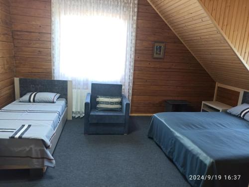 a bedroom with two beds and a chair and a window at Садиба Буквиця in Migovo