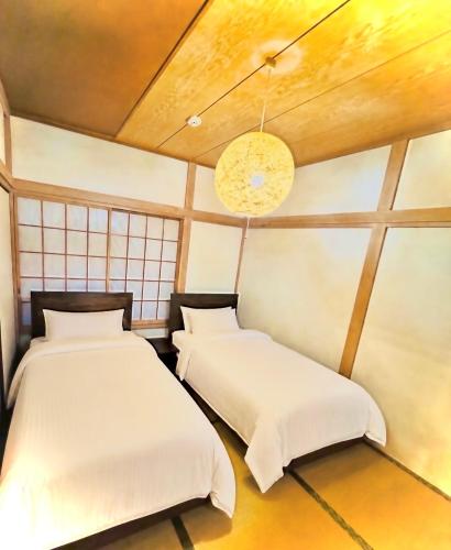 two beds in a room with white sheets at Harbor Terrace Izu OceanView in Ito