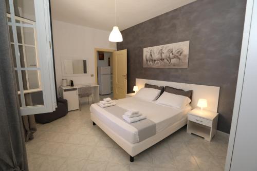 a bedroom with a large white bed and a bathroom at Helios Rooms in Quartu SantʼElena