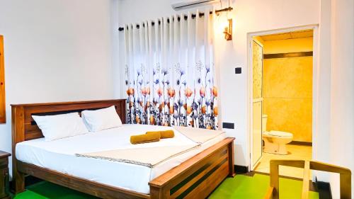 a bedroom with a bed and a bathroom with a toilet at Surf and stay in Weligama