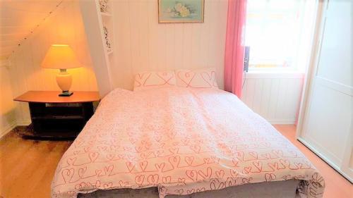 a bedroom with a pink bed with a table and a lamp at Egil's Vacation House in Lillehammer